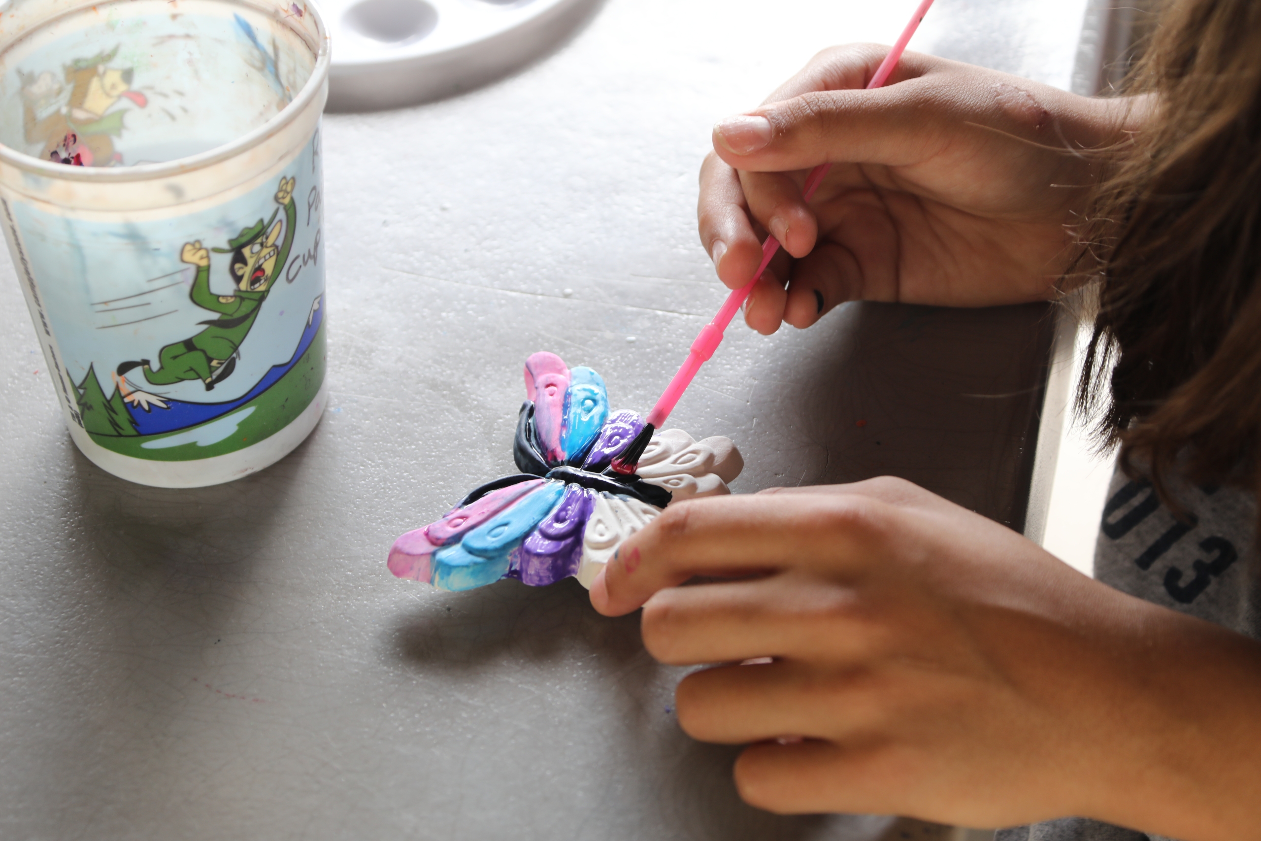 close up of a camper painting a ceramic butterfly